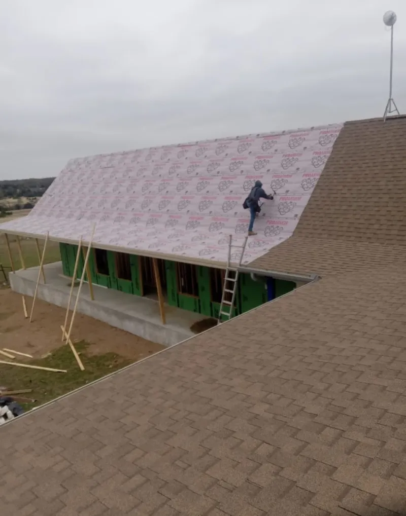 Worker preparing underlayment for a metal roof installation in Eaton